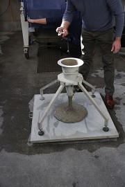 OTH-Conference: The fresh concrete pours onto the measuring plate in a controlled manner, while the duration is measured with a stopwatch