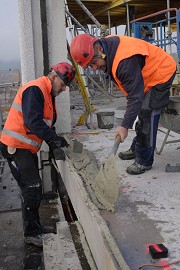 Members of the precast element assembly team are preparing the mortar bed onto which the precast element is placed